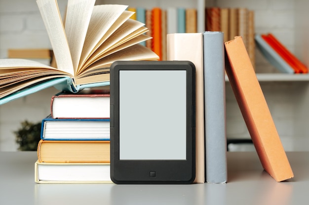 Foto e-book-reader auf dem tisch vor bücherregalen