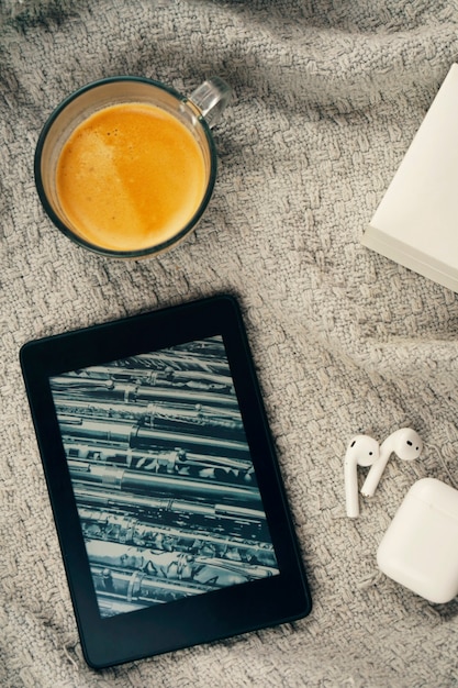 E-Book-Reader, eine Tasse Kaffee und ein Kopfhörer.