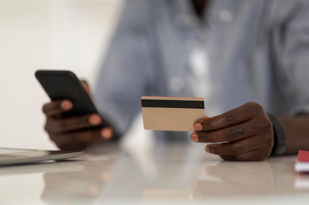 E-Commerce-Konzept Nicht erkennbarer afroamerikanischer Mann mit Smartphone und Kreditkarte