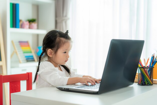 E-Learning der asiatischen Kindergartenschüler-Videokonferenz mit Lehrer auf Laptop im Wohnzimmer zu Hause. Homeschooling und Fernunterricht, Online, Bildung schützen vor dem COVID-19-Virus.