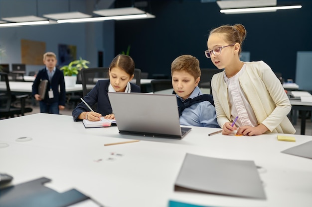 E-Learning für Studierende der Digital Natives über einen Laptop-Computer. Beschäftigte IT-Gruppe für Kinder, die am Schreibtisch sitzt