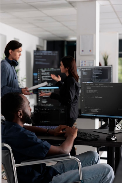 É programador em cadeira de rodas digitando código html no escritório de codificação, trabalhando no programa do servidor com computador. Desenvolvedor web afro-americano com deficiência crônica escrevendo script com algoritmos do sistema.