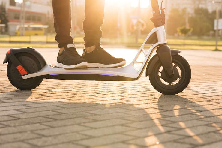 Foto e-scooter-fahrer, mitfahrgelegenheit oder privater öko-transport. männlicher hipster, der eine elektrorollerstraße fährt, um auf moderne weise zu arbeiten. schneller elektrischer transport, morgenlicht