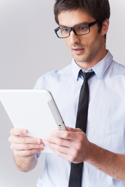 É simplesmente incrível! jovem surpreso de camisa e gravata olhando para tablet digital