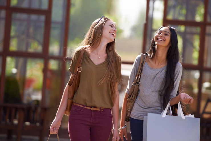 Foto é um ótimo dia para fazer compras duas jovens atraentes com suas sacolas de compras após um dia de terapia de compras