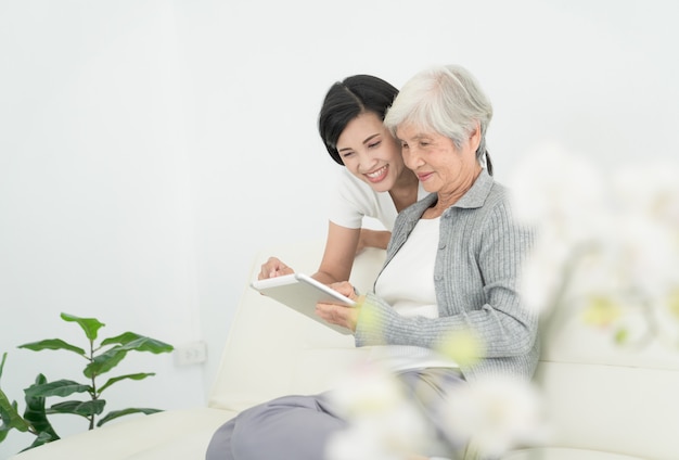 Ealry madre con hija usando tableta digital juntos en casa. Familia sonriente mirando la pantalla, compras en línea