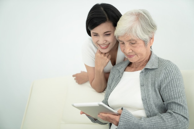 Ealry mãe com filha usando tablet digital juntos em casa. Família sorridente, olhando para a tela, compras on-line