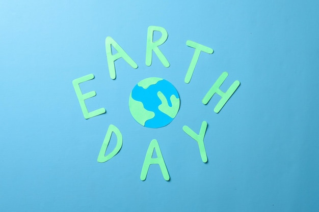 Earth Day Schriftzug Surround Globus aus Papier isoliert auf blauem Hintergrund. welttag der erde.