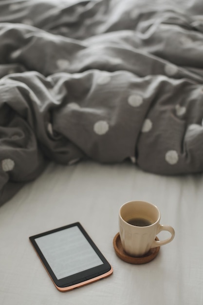 Ebook und eine Tasse Kaffee im Bett auf dem Bettlaken Guten Morgen Frühstück im Bett