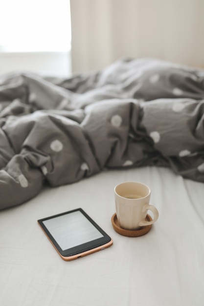 Ebook und eine Tasse Kaffee im Bett auf den Laken Guten Morgen Frühstück im Bett