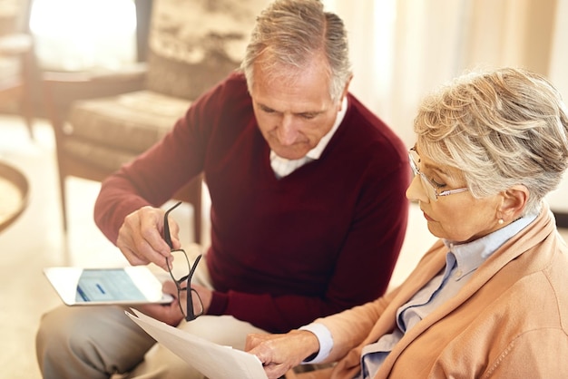 Echando un vistazo a sus finanzas Foto de una pareja de ancianos elaborando un presupuesto mientras están sentados en el sofá de la sala