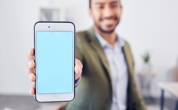 Echar un vistazo. Captura recortada de un joven hombre de negocios irreconocible que muestra la pantalla de su celular a la cámara mientras está sentado en su oficina.