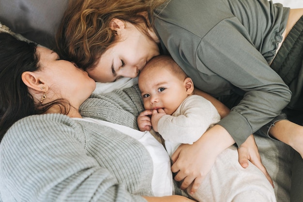 Echte Familie aus junger Mutter und zwei Kindern unterschiedlichen Alters, Teenager-Mädchen und kleiner Junge, die sich im Bett amüsieren