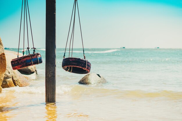 Echte Natur Schönheit Sommer Ozean Landschaft Hintergrund hängen Seil Schaukel alte Reifen malen rot blau klar Meer blau Skyline Sandstrand Wasser Rand gelb Felsen Tag Sonne Freude Spaß Paradies Urlaub romantisch