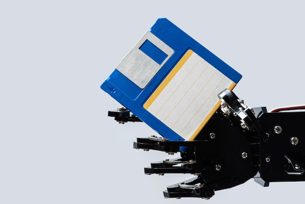 Echte Roboterhand mit Floppy-Disk-Konzepten der KI-Entwicklung und Datenspeicherung