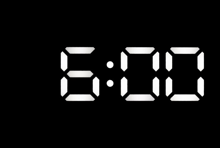 Foto echte weiße led-digitaluhr auf schwarzem hintergrund, die die zeit 600 anzeigt