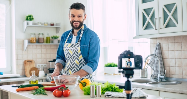 Echter Mann Küchenblog zu Hause, während Kerl frischen gesunden veganen Salat kocht