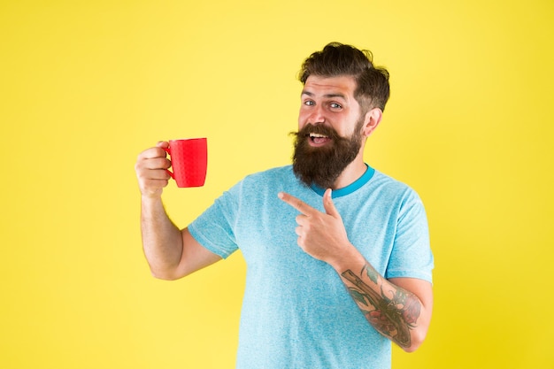 Echter Spezialitätenkaffee entwickelt sich zu einem großen Geschäft. Energiekonzept. Hipster Barista gelber Hintergrund. Café. Bärtiger Mann trinkt Morgenkaffee. Teezeit. Cappuccino mit dem richtigen Milchanteil.