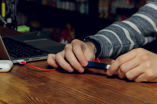 Foto ecigarette pod o dispensador de vapor de nicotina que se carga en una computadora portátil moderna con pods