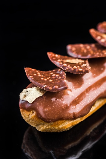 Eclair artesanal francés sobre fondo negro reflectante Espacio de copia