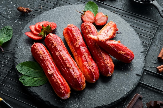 Eclair con crema de fresa Postre de fresa en un plato de piedra negra Vista superior Estilo rústico