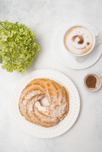 Eclair de bolo de creme com café e hortênsias em fundo cinza