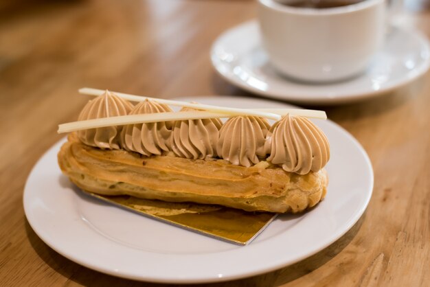 Éclair de café francês no prato com uma xícara de chá