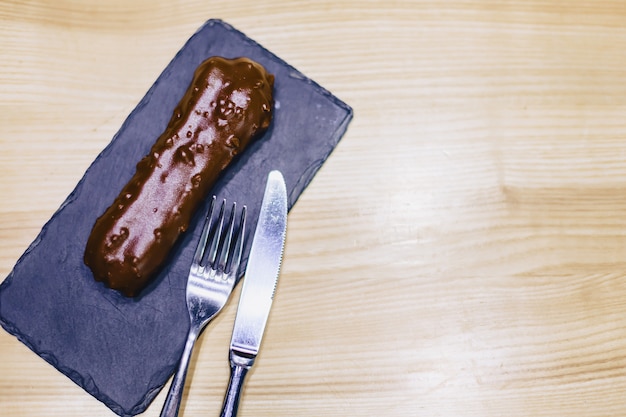 Eclair de chocolate delicioso com um garfo e uma faca