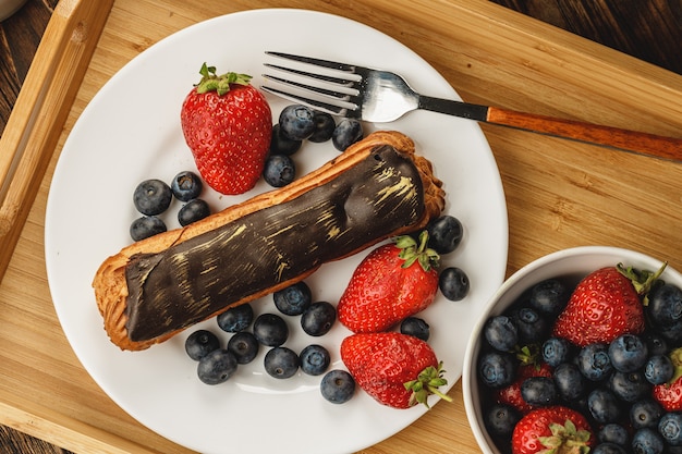 Eclair-Kuchen mit Schokoladenglasur auf Holztablett