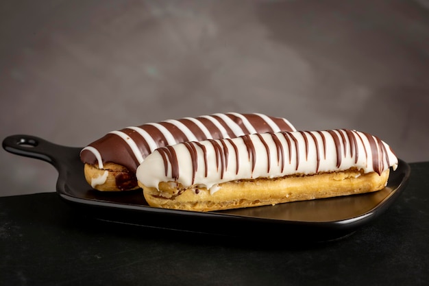 Eclair Leckeres Schokoladen-Eclair auf dem Tisch