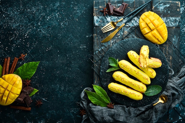 Eclair mit Mangocreme Mango-Dessert auf einer schwarzen Steinplatte Draufsicht Rustikaler Stil