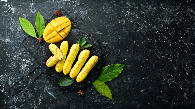 Eclair mit Mangocreme Mango-Dessert auf einer schwarzen Steinplatte Draufsicht Rustikaler Stil