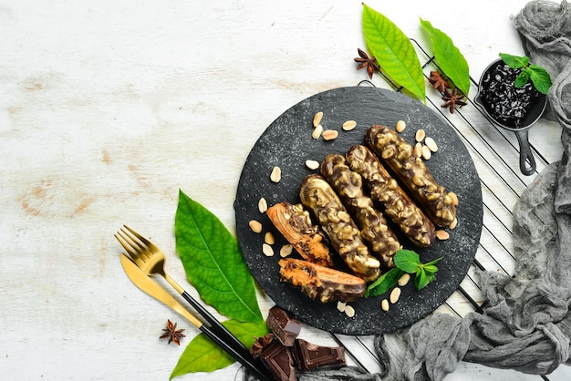 Eclair mit Schokoladen-Erdnuss-Creme Schokoladen- und Nuss-Dessert auf einer schwarzen Steinplatte Draufsicht Rustikaler Stil