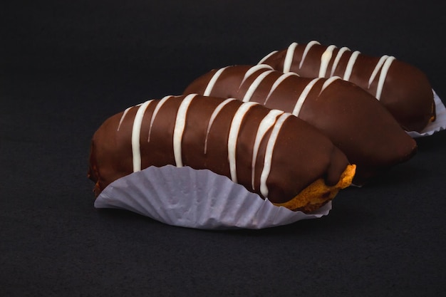 Eclair mit Schokoladenfüllung auf schwarzer Oberfläche.
