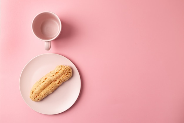 Eclair no prato. Fundo rosa pastel. Sobremesa. conceito, minimalismo