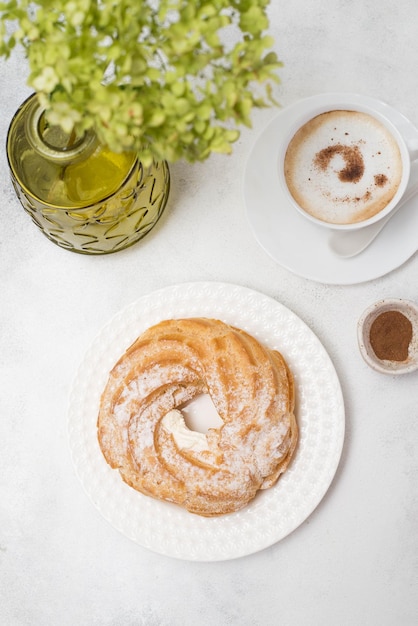 Eclair de pastel de crema pastelera con café y hortensias sobre fondo gris