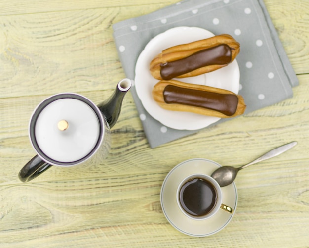 Eclairs y café sobre un fondo de madera