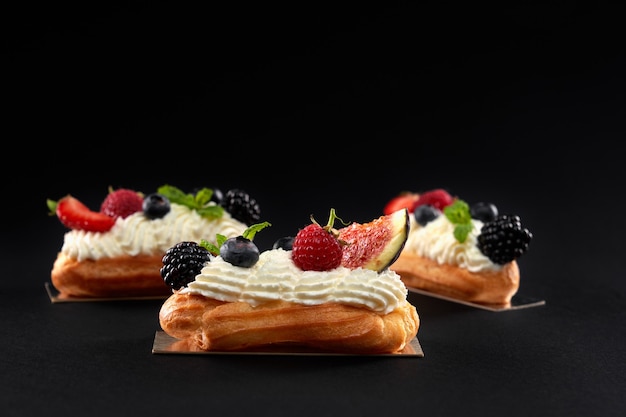 Éclairs caseiros com creme e frutas vermelhas.