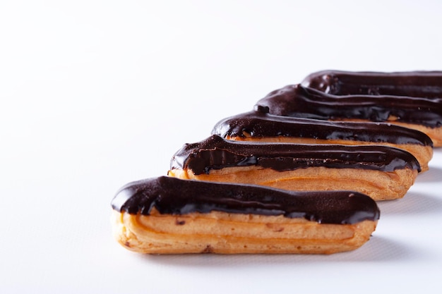 Eclairs cheios de cobertura de chocolate em um fundo branco