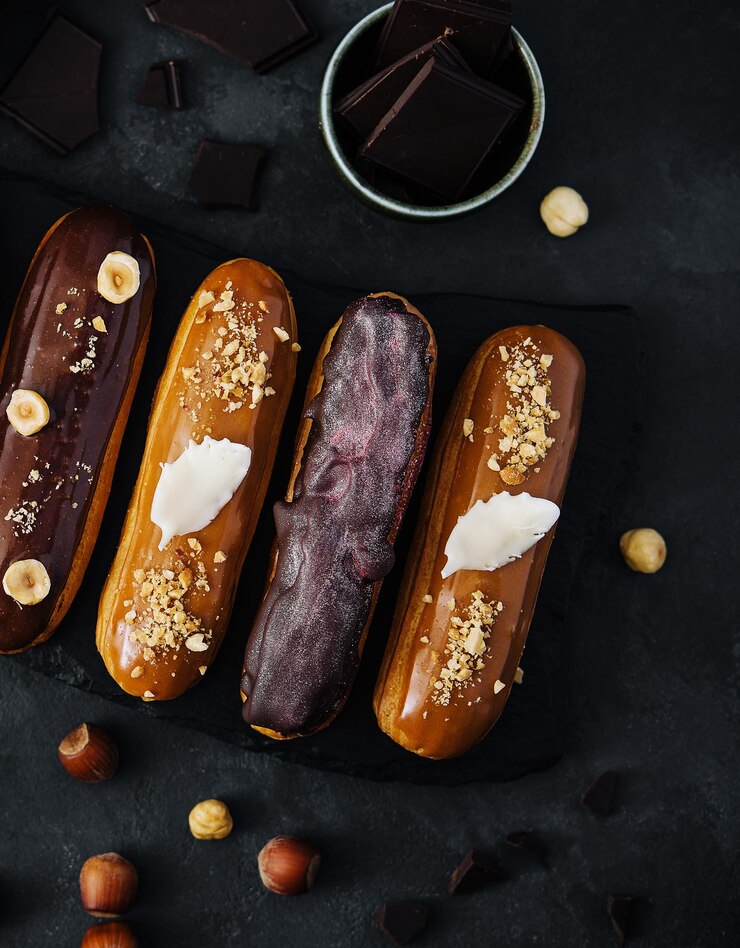 Eclairs de chocolate dulce en tablero de madera negro