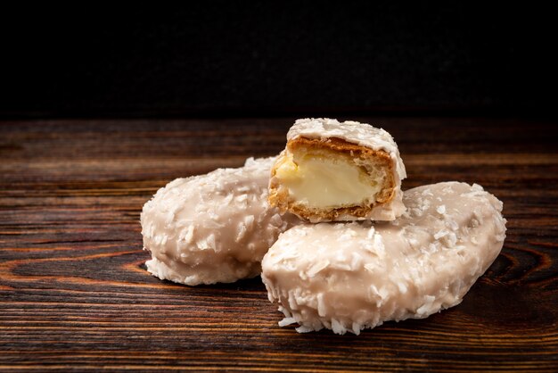 Eclairs de coco o galletas de natillas en la mesa de madera oscura.