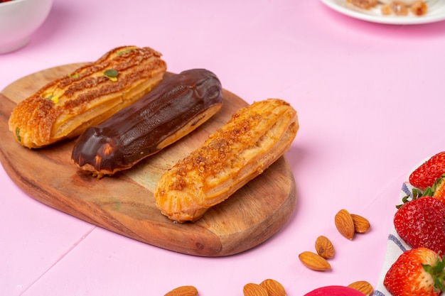 Eclairs de bolo caseiro na mesa-de-rosa