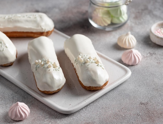 Eclairs de esmalte de chocolate branco na tábua de servir Foco seletivo de sobremesa tradicional francesa