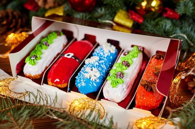 Éclairs de natal com recheios de cereja e creme em um fundo de guirlandas brilhantes