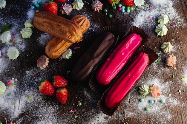 Éclairs de sobremesas francesas tradicionais com esmalte na mesa de doces