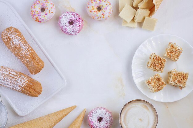 Eclairs y donuts con café sobre un fondo de mármol, Fondo claro, Confitería al estilo de un blogger, Espacio de copia