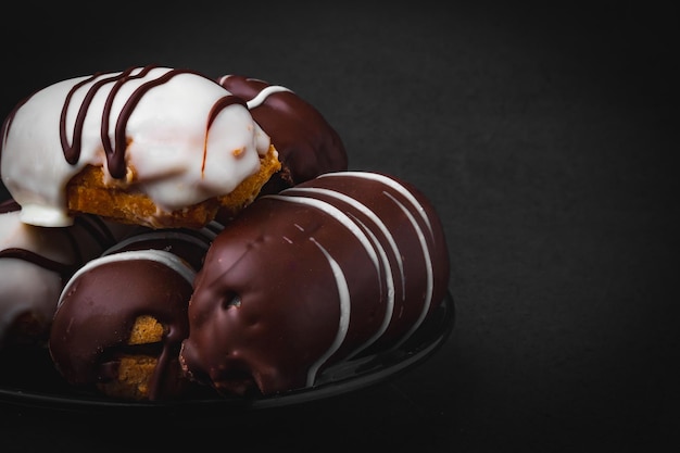 Eclairs con dulce de leche y relleno de chocolate sobre superficie negra.