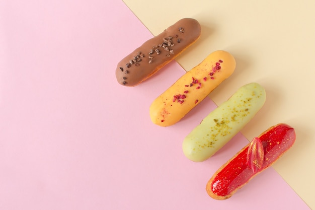 Éclairs em um fundo mínimo. natureza morta, olá, humor para sobremesa. sobremesa francesa tradicional com glacê colorido. cozimento de conceito, receitas de livro de receitas, banner de padaria, anúncio de café.