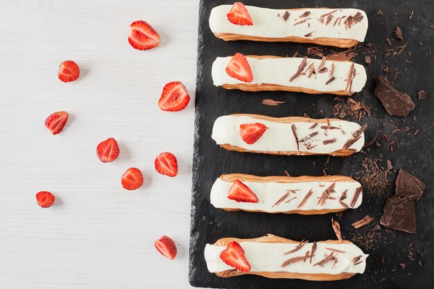 Eclairs con fresas y chocolates sobre un fondo claro