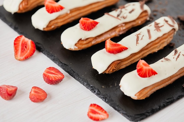 Eclairs con fresas y chocolates sobre un fondo claro